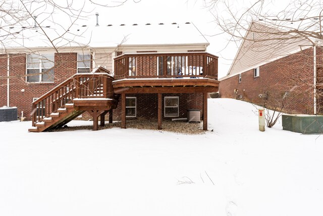 snow covered house featuring central AC and a wooden deck