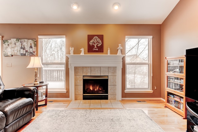 living room featuring a tile fireplace, hardwood / wood-style floors, and a healthy amount of sunlight