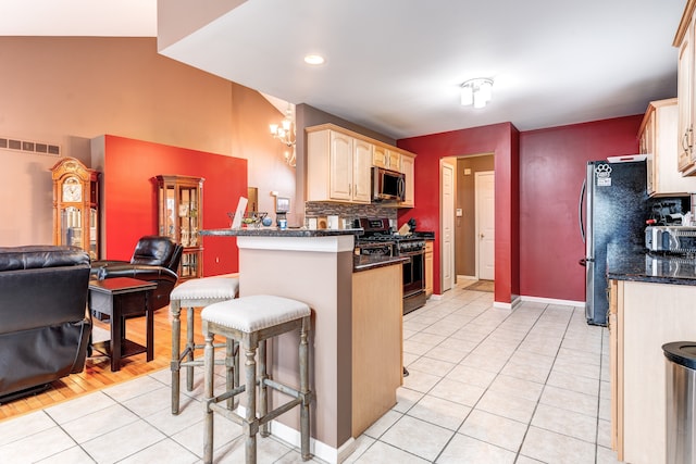 kitchen with light tile patterned flooring, a kitchen breakfast bar, kitchen peninsula, and appliances with stainless steel finishes