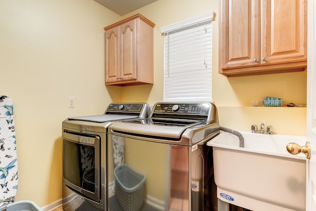 washroom featuring sink, washing machine and dryer, and cabinets