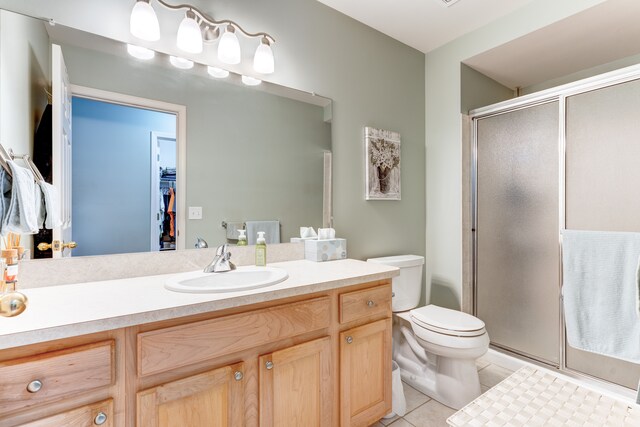 bathroom with toilet, an enclosed shower, tile patterned flooring, and vanity