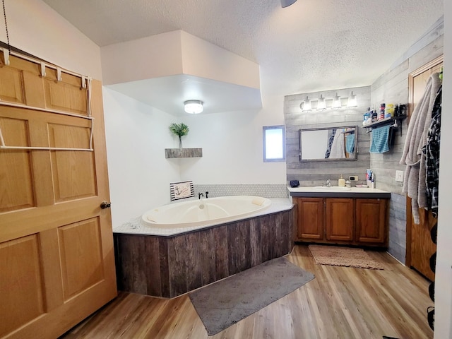 bathroom with wood-type flooring, vanity, a textured ceiling, and a bathing tub