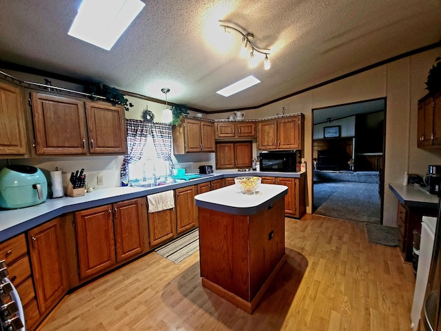 kitchen featuring light wood-type flooring, a textured ceiling, hanging light fixtures, and a center island