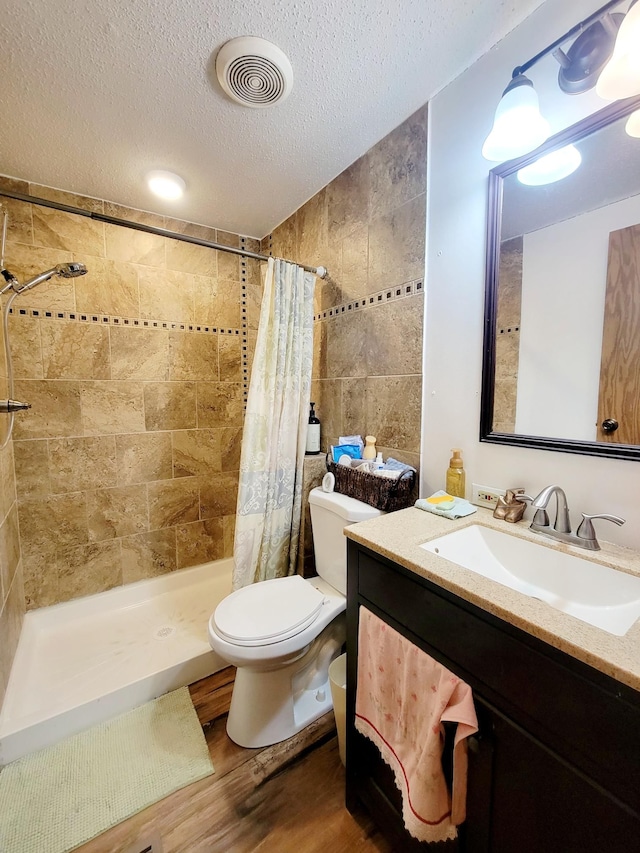 bathroom with toilet, a textured ceiling, hardwood / wood-style floors, a shower with shower curtain, and vanity