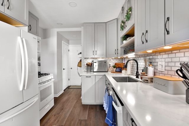 kitchen featuring backsplash, sink, white appliances, gray cabinetry, and dark hardwood / wood-style flooring