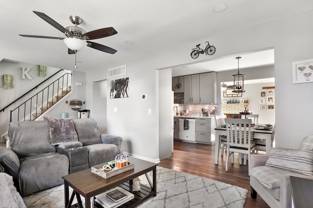 living room with ceiling fan with notable chandelier and hardwood / wood-style floors