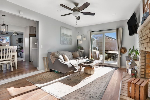 living room with ceiling fan, dark wood-type flooring, and a brick fireplace