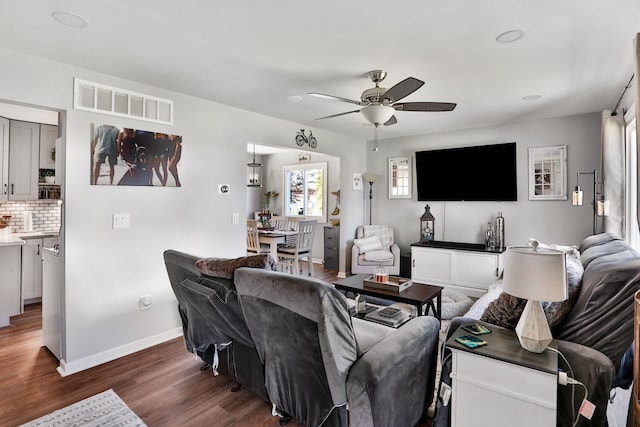 living room featuring dark wood-type flooring and ceiling fan