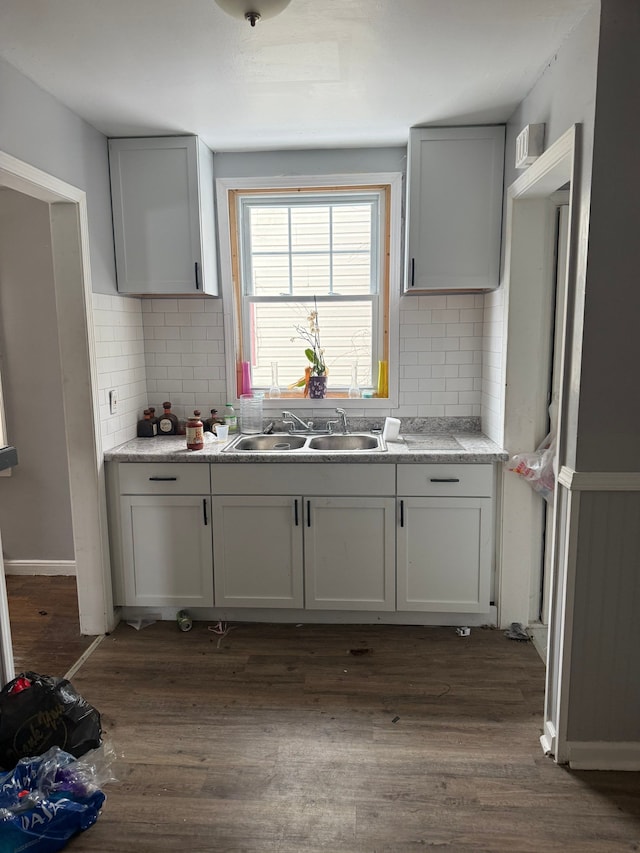 kitchen featuring sink, white cabinets, dark hardwood / wood-style floors, decorative backsplash, and light stone countertops