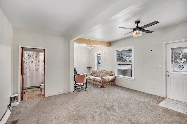 living area featuring ceiling fan, beam ceiling, and carpet floors