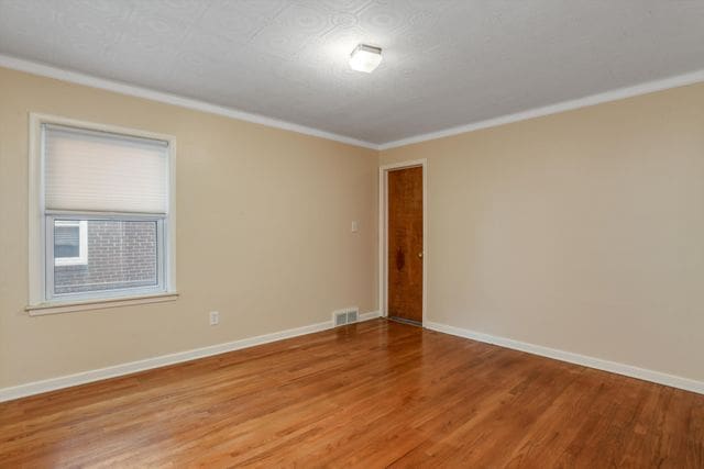 empty room with crown molding and hardwood / wood-style floors