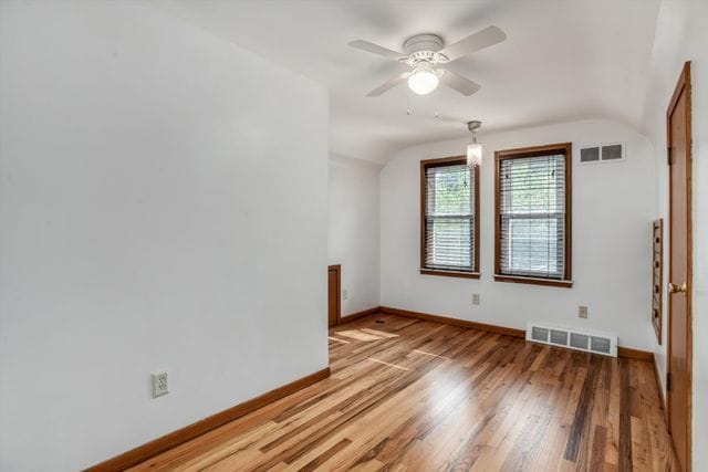 empty room with ceiling fan, vaulted ceiling, and hardwood / wood-style floors