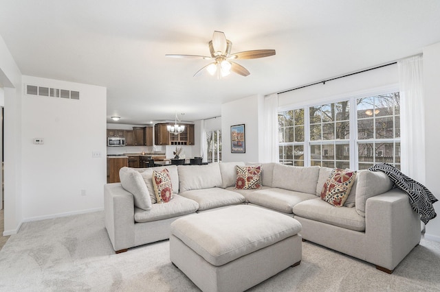 living room with light colored carpet and ceiling fan with notable chandelier