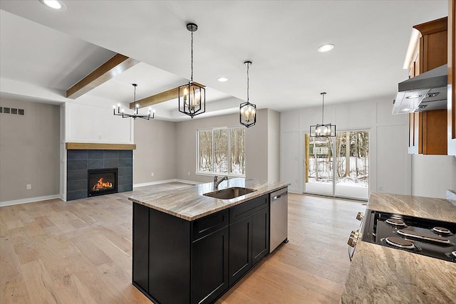 kitchen featuring sink, decorative light fixtures, light stone counters, an island with sink, and extractor fan