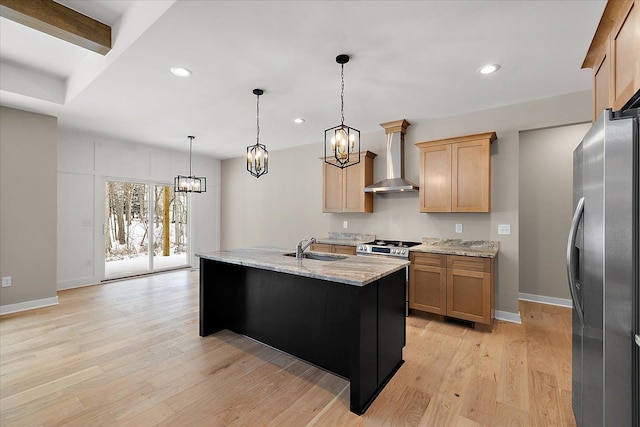 kitchen with light stone counters, wall chimney exhaust hood, a center island with sink, pendant lighting, and appliances with stainless steel finishes