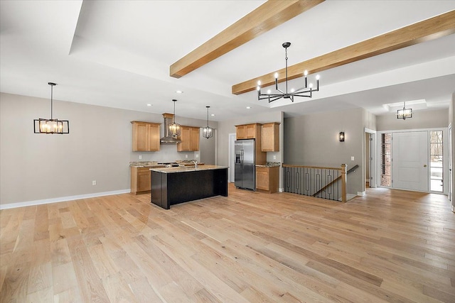 kitchen featuring a kitchen island with sink, light hardwood / wood-style floors, hanging light fixtures, wall chimney exhaust hood, and stainless steel refrigerator with ice dispenser