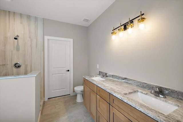 bathroom featuring toilet, walk in shower, and vanity