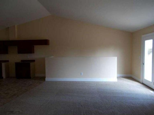 unfurnished living room with carpet floors and vaulted ceiling