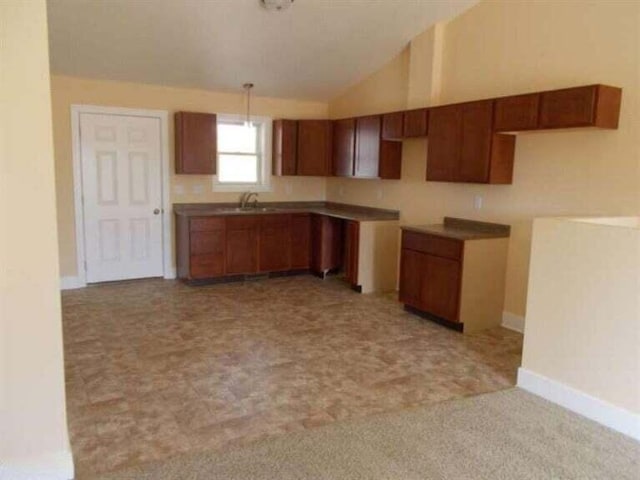 kitchen featuring pendant lighting, vaulted ceiling, and light colored carpet