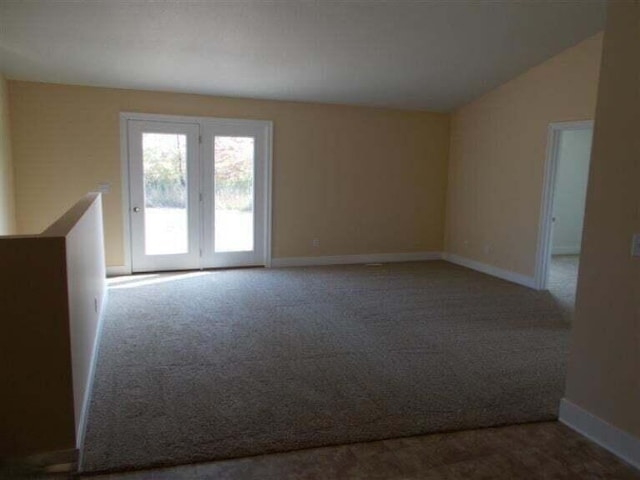 carpeted spare room with vaulted ceiling