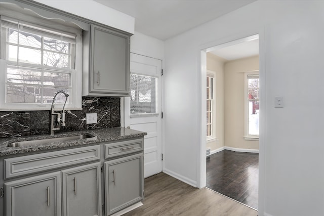 21746-48 Moross Rd, Grosse Pointe, MI 48236 - kitchen with gray cabinets, a sink, backsplash, wood finished floors, and stone countertops