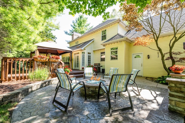 rear view of house featuring a gazebo, a fire pit, a deck, and a patio area