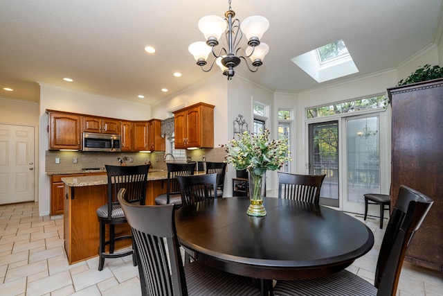 tiled dining area featuring an inviting chandelier, a skylight, and crown molding