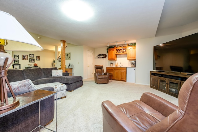 living room with rail lighting, bar, and light colored carpet