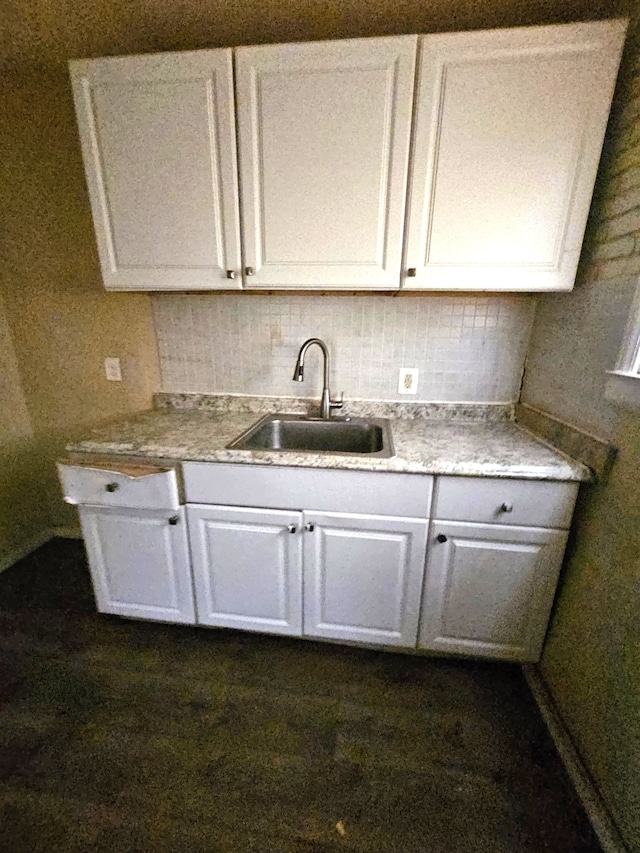 kitchen featuring white cabinetry, sink, and tasteful backsplash