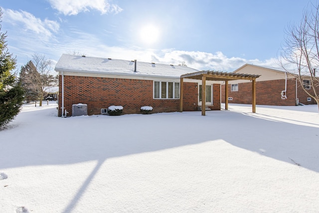 snow covered rear of property with a pergola