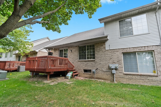 rear view of house featuring a wooden deck and a yard