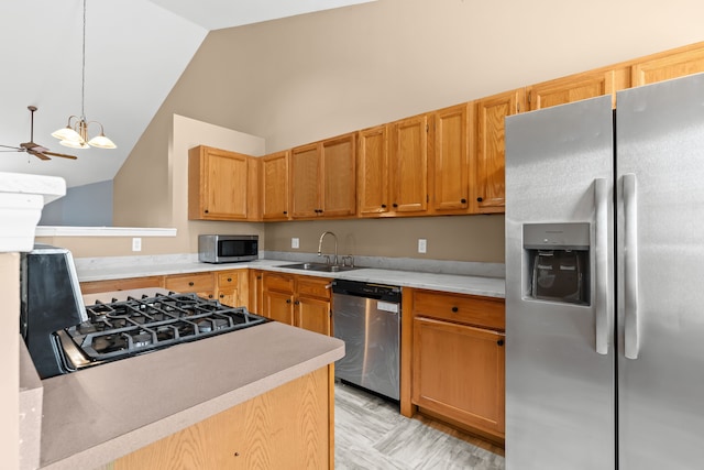 kitchen with sink, vaulted ceiling, hanging light fixtures, appliances with stainless steel finishes, and ceiling fan with notable chandelier