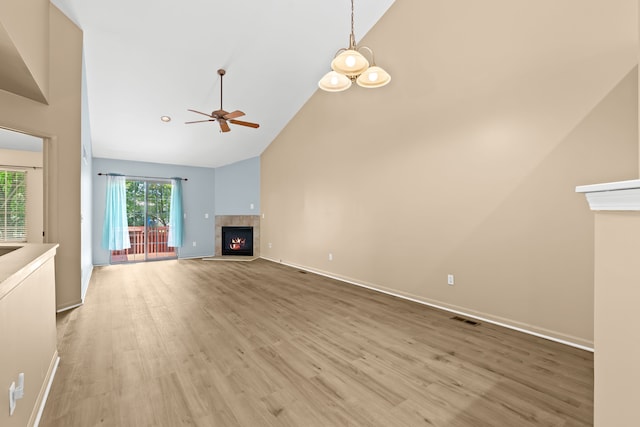 unfurnished living room with high vaulted ceiling, light hardwood / wood-style flooring, a tile fireplace, and ceiling fan