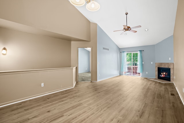 unfurnished living room featuring a tiled fireplace, high vaulted ceiling, ceiling fan, and light wood-type flooring