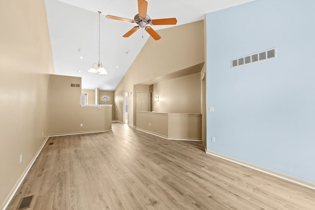 unfurnished living room featuring ceiling fan with notable chandelier, high vaulted ceiling, and light hardwood / wood-style flooring