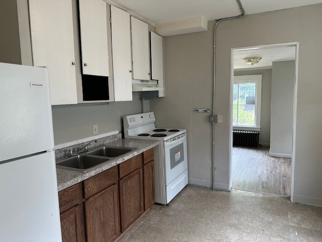 kitchen with white appliances, white cabinetry, sink, and radiator