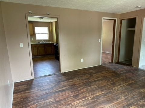 empty room featuring a textured ceiling and dark hardwood / wood-style floors