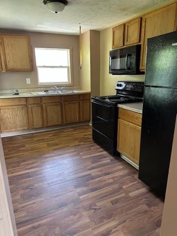 kitchen featuring sink, dark hardwood / wood-style flooring, and black appliances