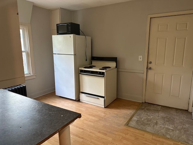 kitchen featuring white appliances, light hardwood / wood-style floors, and radiator