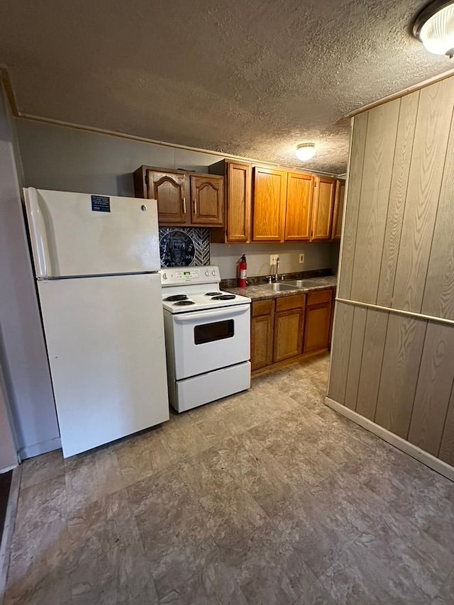 kitchen featuring white appliances, a textured ceiling, and wood walls