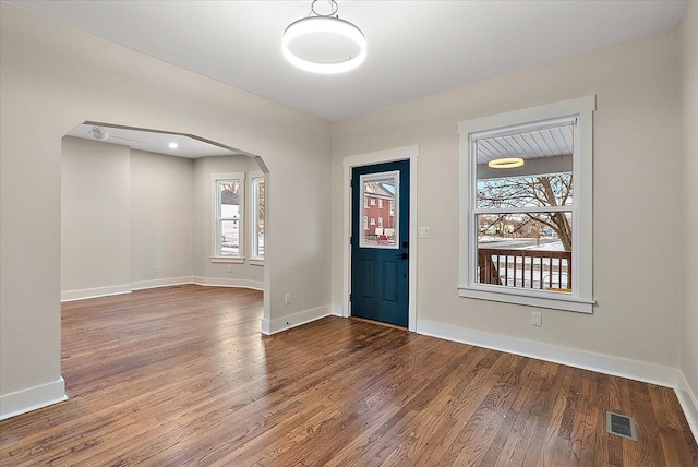 entryway featuring arched walkways, wood finished floors, visible vents, and baseboards