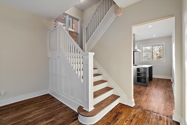 stairs featuring beverage cooler, baseboards, wood finished floors, and recessed lighting