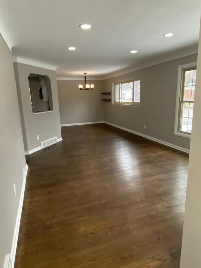 unfurnished room with an inviting chandelier and dark hardwood / wood-style floors