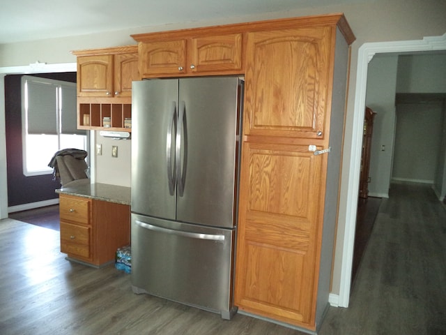 kitchen featuring dark stone countertops, dark hardwood / wood-style floors, and stainless steel refrigerator