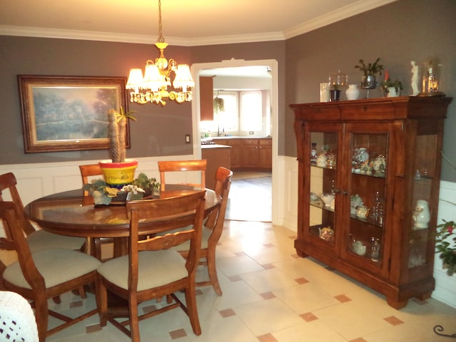 dining space featuring a chandelier, crown molding, and sink