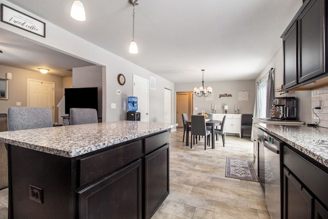 kitchen with light hardwood / wood-style floors, decorative backsplash, a kitchen island, decorative light fixtures, and stainless steel dishwasher