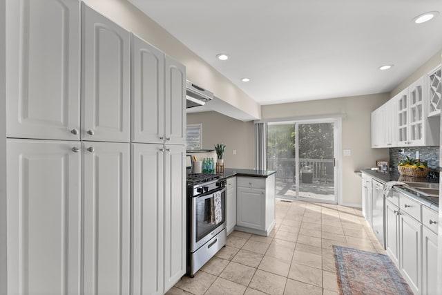 kitchen featuring stainless steel range with gas stovetop, light tile patterned floors, white dishwasher, white cabinets, and backsplash