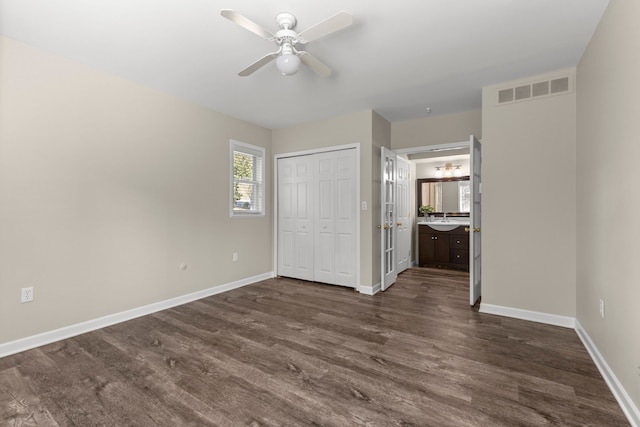 unfurnished bedroom featuring connected bathroom, a closet, ceiling fan, dark hardwood / wood-style floors, and sink