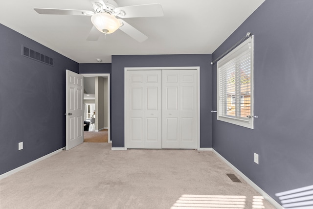 unfurnished bedroom featuring ceiling fan, a closet, and light carpet