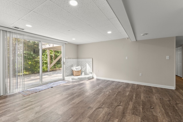 unfurnished living room with a paneled ceiling and dark wood-type flooring